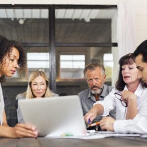 Business people using laptop at meeting in office