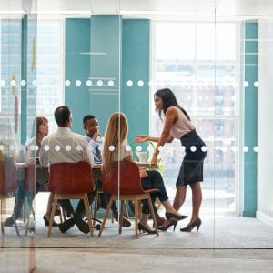 Female boss stands leaning on table at business meeting