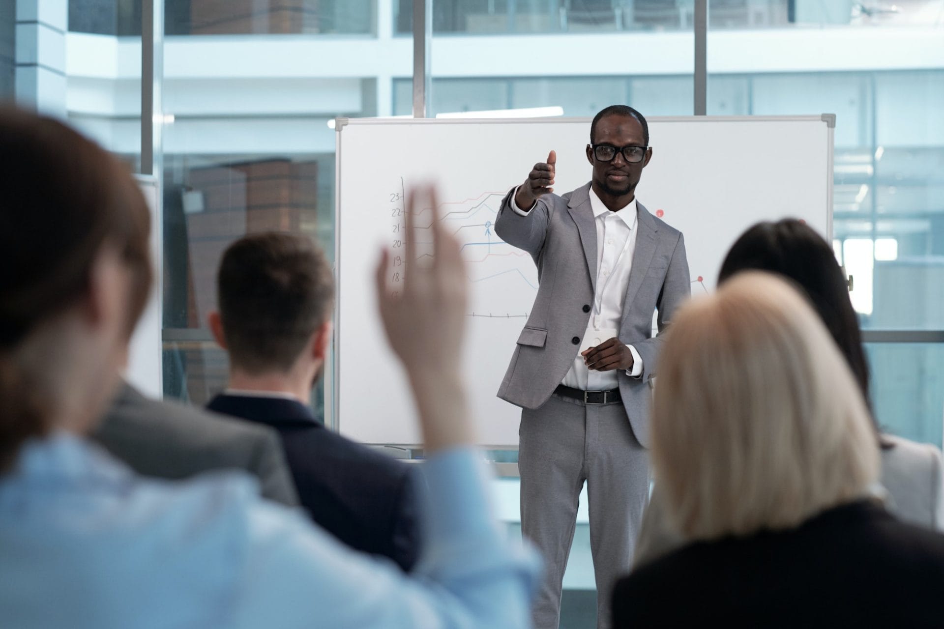 Young African American male business coach pointing at one of colleagues