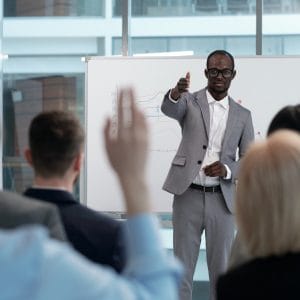 Young African American male business coach pointing at one of colleagues